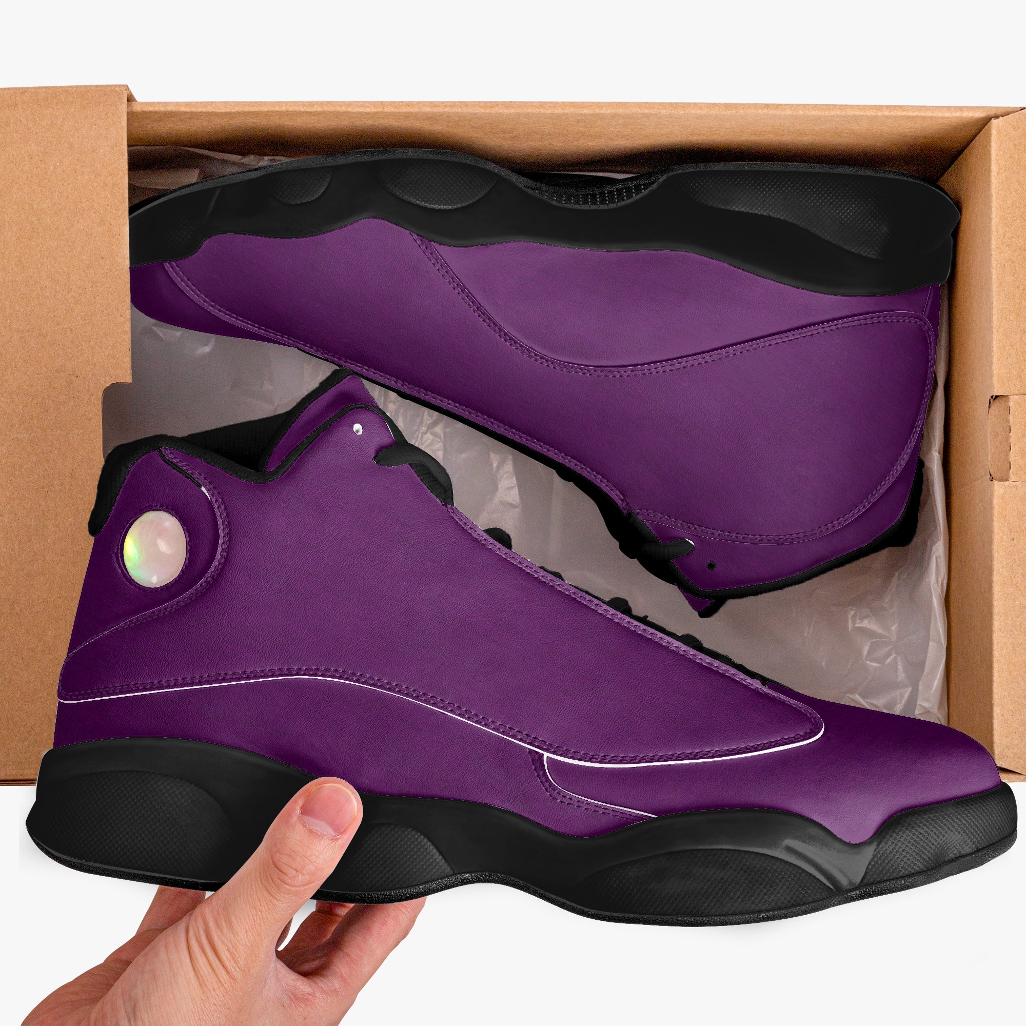 High-top purple leather basketball sneakers with black soles and iridescent circular logo in cardboard box.