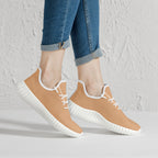 Beige low-top knit sneakers with white soles and laces, worn with cuffed blue jeans.