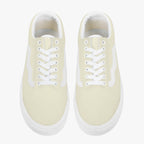 Pale yellow low-top canvas sneakers with white laces and thick white rubber soles.