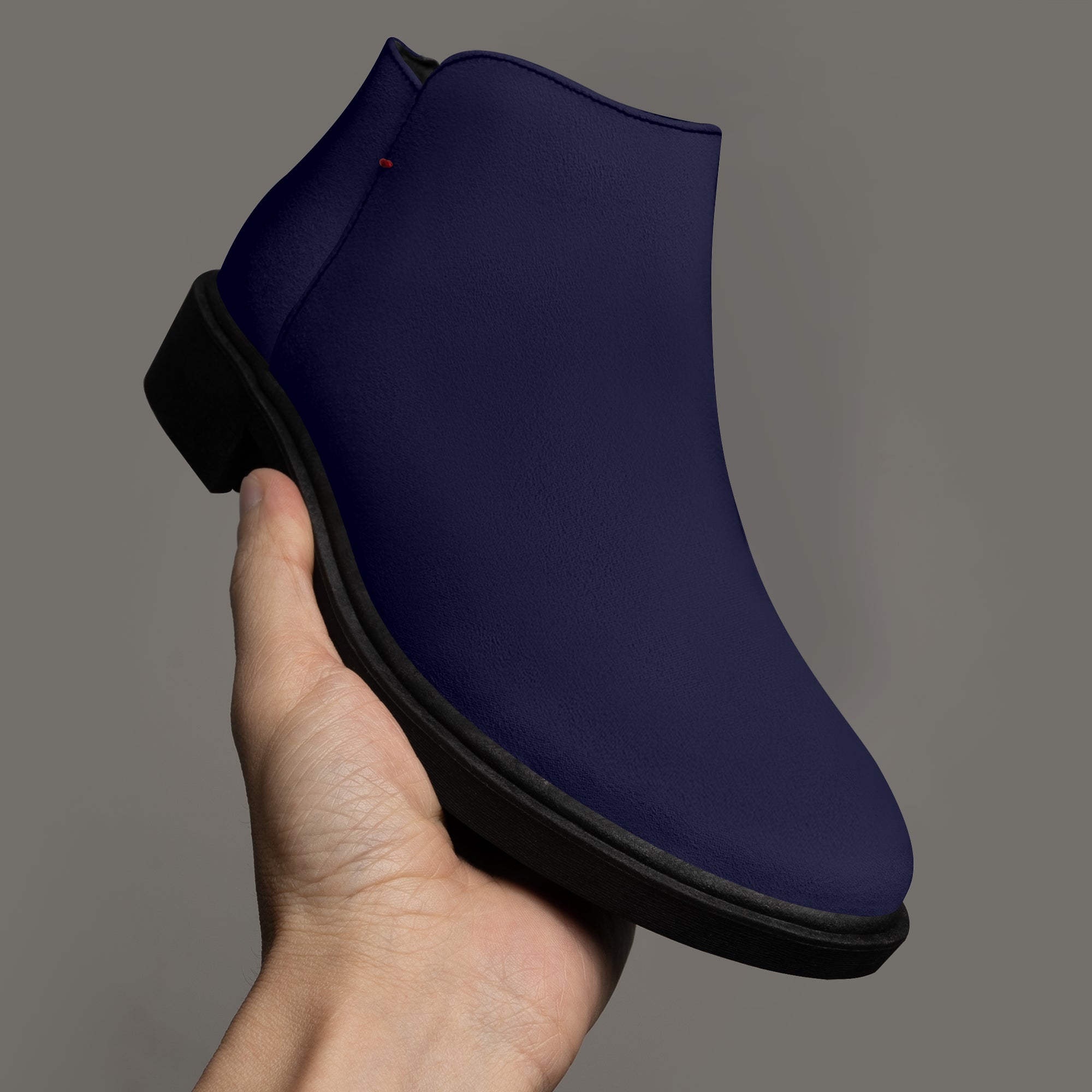 Navy blue slip-on bootie with chunky black heel and red accent stitching.